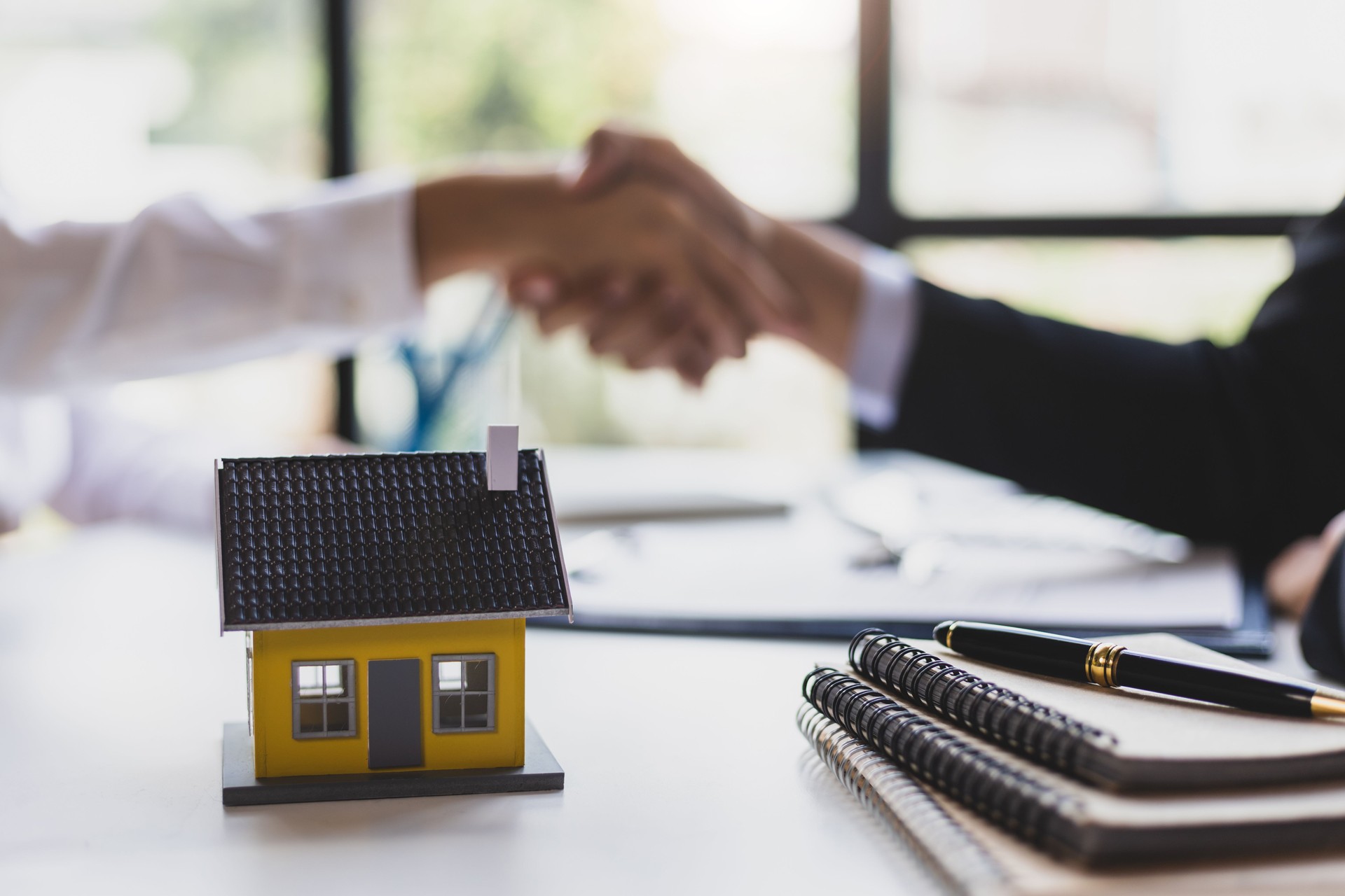 Businessman shaking hands with real estate agent in office after reaching home purchase agreement.